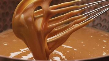 Melted caramel dripping from whisk, closeup food shot. video