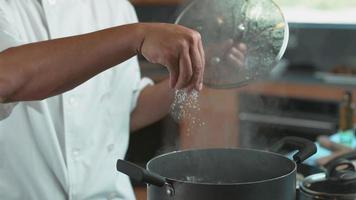 le chef fait tomber du sel dans une casserole en super ralenti, filmé avec une caméra fantôme 4k flex. video