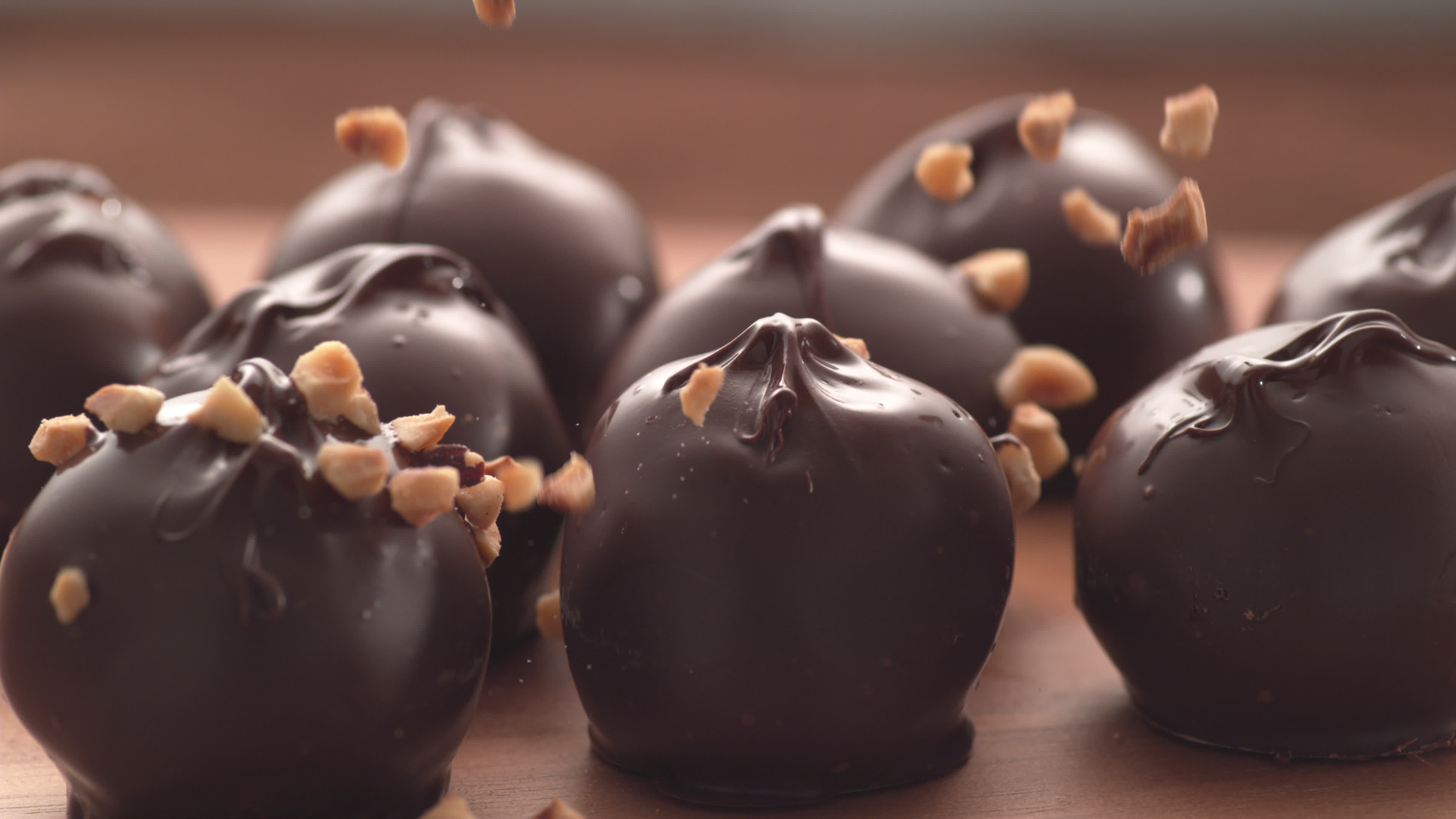 Nuts falling onto chocolate truffles in super slow motion. Shot on