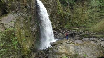 Aerial shot of backpacker standing in front of waterfall video