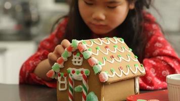 Nahaufnahme eines jungen Mädchens, das Lebkuchenhaus zu Weihnachten dekoriert? video