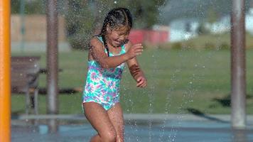 flicka som leker i sprinkler på park i super slow motion video