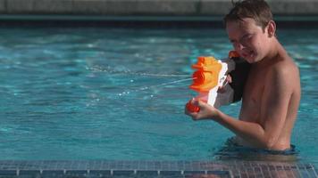 Junge spritzt Wasserpistole im Pool, super Zeitlupe video