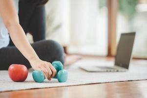 Woman's hand picking up dumbbell on living room floor photo