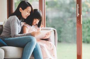 Happy Asian family using digital tablet to study together at home