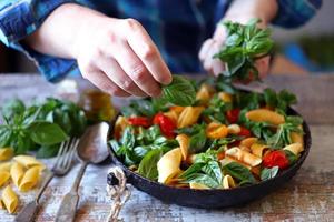 Chef mixes pasta with basil and spices in a pan photo