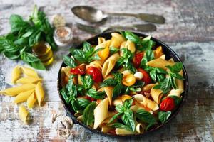 Pasta in a pan with tomatoes basil and spices photo