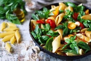 Pasta in a pan with tomatoes basil and spices photo