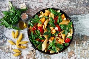 Pasta in a pan with tomatoes basil and spices photo