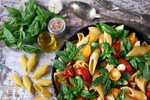 Pasta in a pan with tomatoes basil and spices photo