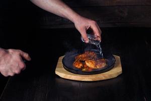 fajitos, meat in a frying pan with fire on a wooden tray, beautiful serving, dark background photo