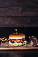 cheeseburger on a wooden tray in a restaurant, on a dark background photo