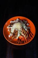 oriental salad with chicken on an orange plate, beautiful serving, dark background photo