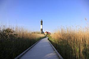 Black and white lighthouse on the ocean as the sun is setting photo