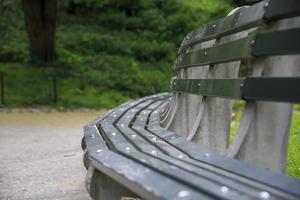 Curved green wooden bench in a park in the summer photo