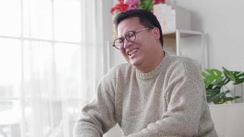 Man laughing and sitting on sofa and  spending time to watch comedy series during the day at home on the weekend alone Happy mood video