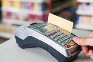 Hand press with swiping credit card on payment terminal in store photo