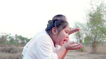 Family of Asian mother and daughter play blowing grass flowers on their hands at beautiful field landscape Mom and girl had smiling and laugh a lot especially child was dancing cause very happy video