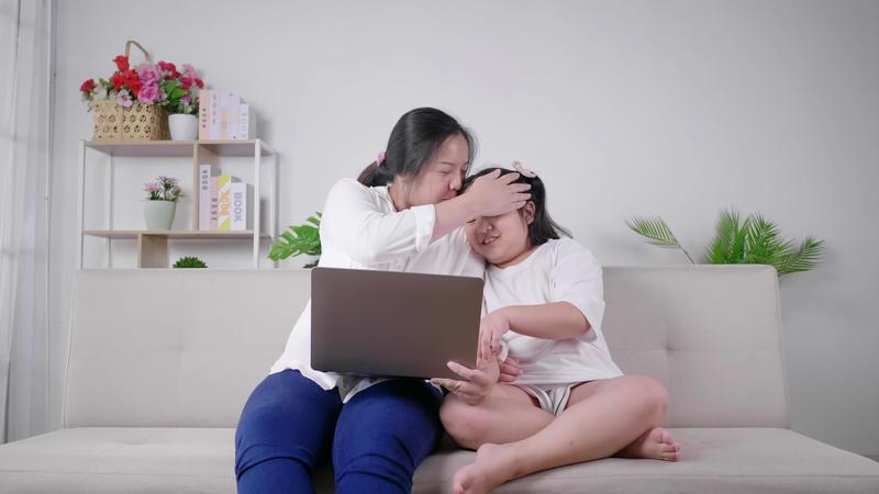 mãe beija filha mãe e filho se divertindo, rindo e assistindo a série dramática da coreia no laptop juntos na sala de estar mãe e filho passando o dia em quarentena 2577939 Vídeo stock no Vecteezy