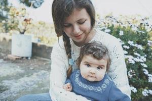 Young mom hugging her baby and enjoying a spring day in the garden photo