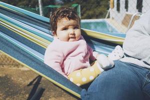 Little baby having fun on a hammock in a sunny day photo