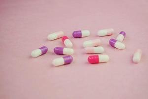 A detailed macro of pills and capsules with pink background photo