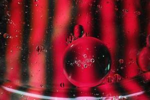 A beautiful and colorful vibrant macro of oil bubbles on water with a pink and black contrast as stripe texture and background pattern photo