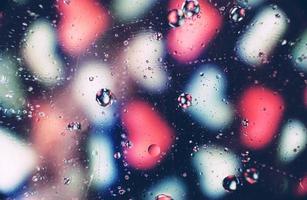 Una hermosa y vibrante macro de burbujas de aceite en el agua con un patrón de corazones blancos y rosados borrosos sobre fondo negro foto