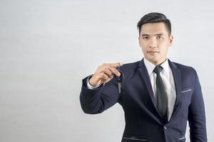 Handsome businessman holding car key on gray background photo