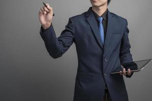 Close up of businessman in blue suit drawing on gray background photo