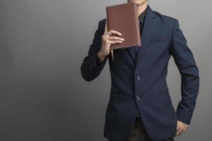 Close up of businessman in blue suit holding books on gray background photo