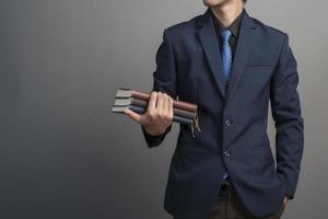 Close up of businessman in blue suit holding books on gray background photo