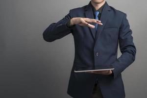 Close up of businessman in blue suit using tablet computer on gray background photo