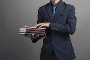 Cerca del empresario en traje azul sosteniendo libros sobre fondo gris foto