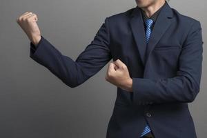 Cerca del empresario en traje azul luchando sobre fondo gris foto