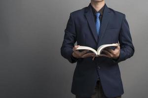 Cerca del empresario en traje azul sosteniendo libros sobre fondo gris foto