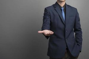 Close up of businessman in blue suit holding something on gray background photo