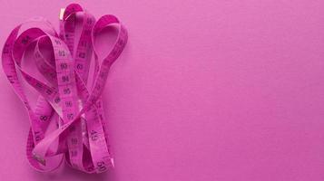 Pink centimeter on pink background. Simple flat lay with pastel texture. Fitness concept. Stock photo. photo