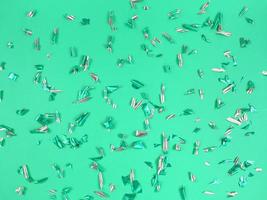 Confetti foil pieces on green background. Abstract festive backdrop. photo