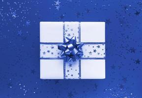 Gift box and stars on a blue background. Monochrome flat lay. photo