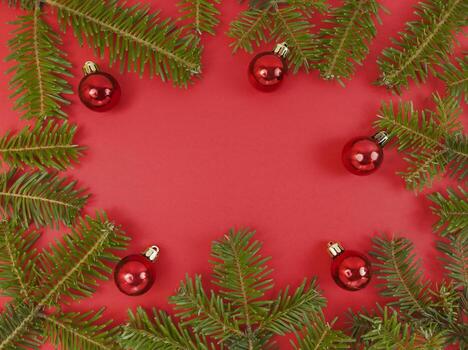 Christmas frame with fir tree branches and baubles on a red background. Festive flat lay with copy space inside. Stock photo. photo