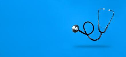 Levitating stethoscope on blue background and shadow under it with copy space. Stock photo. photo