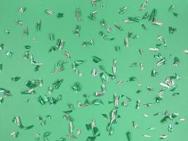 Confetti foil pieces on green background. Abstract festive backdrop. photo