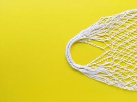 White string cotton eco bag on yellow background. Simple flat lay with copy space. Ecology zero waste concept. Stock photo. photo