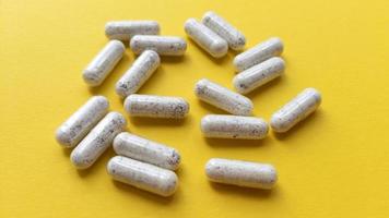 cápsulas de pastillas blancas sobre fondo amarillo. plano simple con textura pastel. concepto médico. foto de stock.
