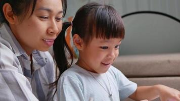 mãe e filhas felizes aprenderam a desenhar no laptop da sala de estar. mãe ajudando as meninas a fazerem um desenho no papel. conceito de escola em casa. aulas online do jardim de infância. video