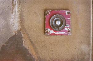 Red doorbell on a brown wall photo