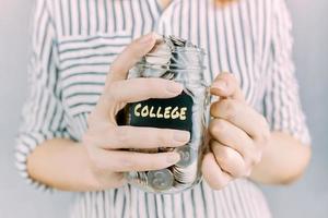 Glass jar with savings for college in woman hands. photo