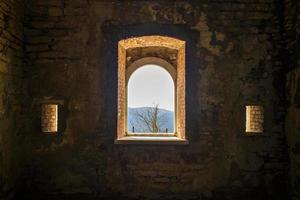 View of trees and mountains through an old window photo