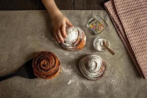 Children's hand takes a freshly baked cinnamon bun photo